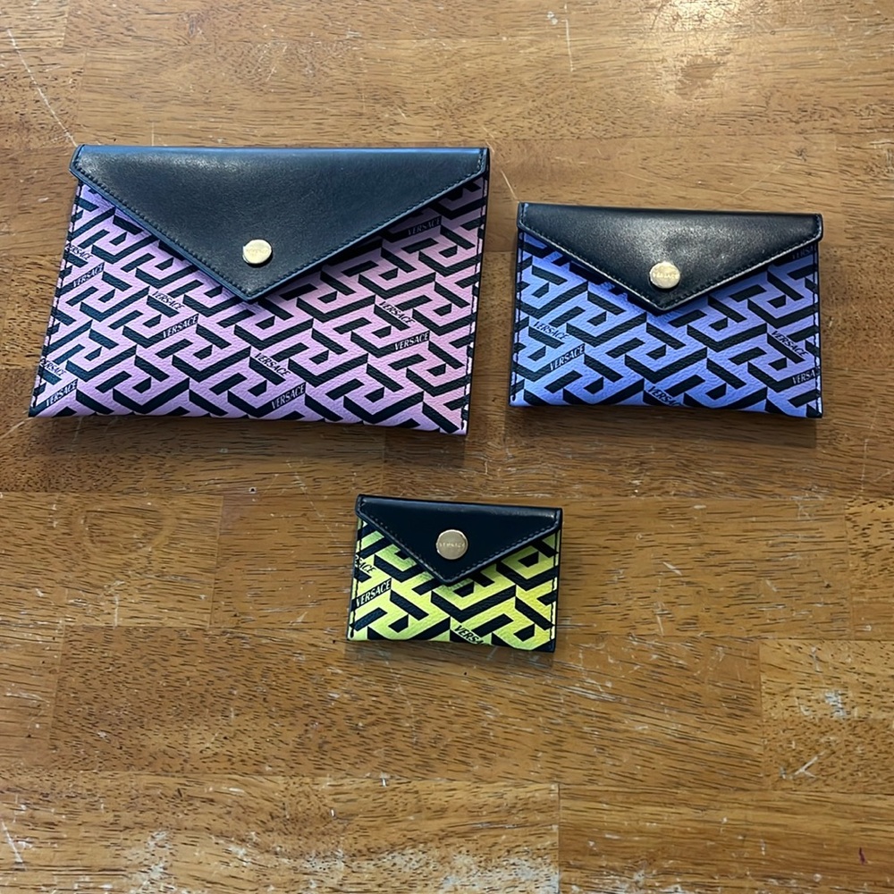 Three pink, yellow, and purple Versace envelope clutch bags